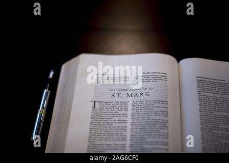 Closeup shot of an open bible near a fountain pen on a wooden surface Stock Photo