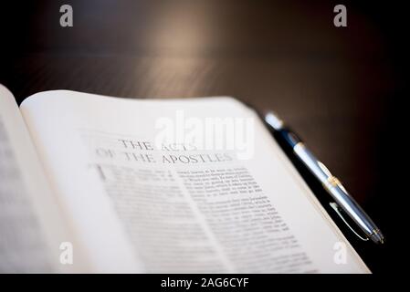 Closeup shot of a pen bible near a fountain pen on a wooden surface with a  blurred background Stock Photo