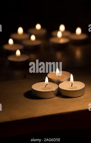 An arrangement of burning tea lights in a darkened space Stock Photo