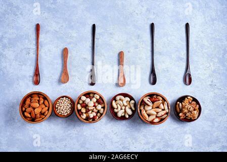 a variety of nuts in wooden bowls pattern on a blue background Stock Photo