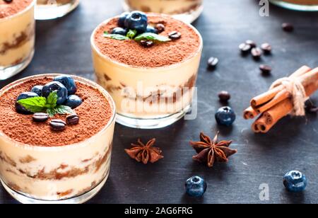 dessert tiramisu in glasses, decorated with blueberries and mint with coffee beans. Stock Photo