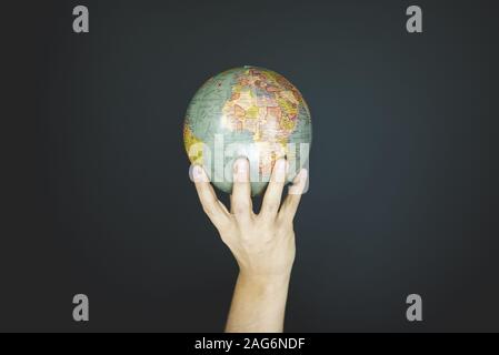 Closeup shot of a person holding a small globe with a black background Stock Photo