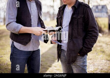 Closeup shot of two males standing near each other and reading the bible with a blurred background Stock Photo