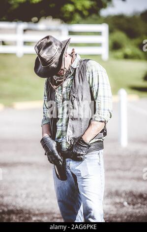 Vertical shot of a cowboy with his hands on the his belt and a blurred background Stock Photo