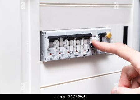 An RCD circuit breaker board with many switches. Man's hand is about switch OFF Stock Photo