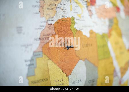 Closeup shot of a black pin on Algeria country on the map with a blurred background Stock Photo