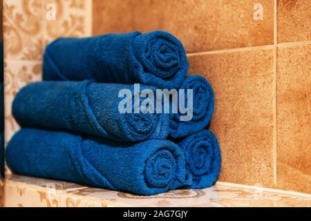 A stack of five bath blue towels rolled up on a shelf in the bathroom Stock Photo