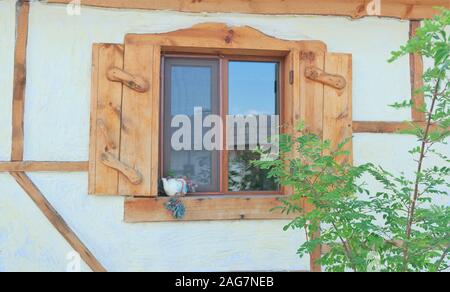 Beautiful shot of a cool window with wooden shutters and a small teapot on the windowsill Stock Photo