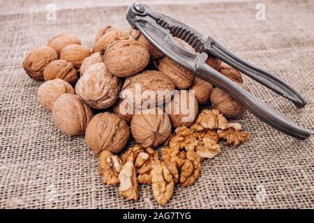 Mature walnuts and Nutcracker on woven fabric. Nuts on linen fabric Stock Photo