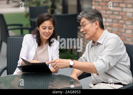 Mature Chinese couple reading menu in restaurant Stock Photo