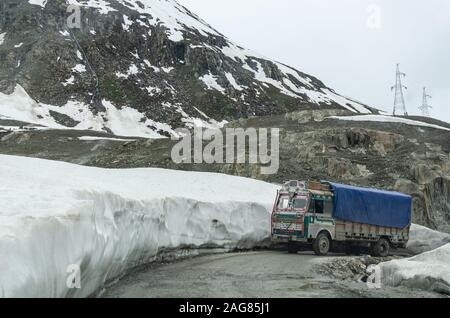 Truck maneuvering a curve on the snow-lined Srinagar - Leh National Highway in May somewhere near the start of Zoji la pass, Jammu and Kashmir, India Stock Photo
