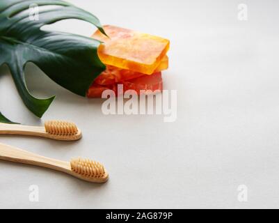 Eco friendly natural bamboo toothbrushes and handmade soap on white background with green  leaves. Zero waste concept, plastic free Stock Photo
