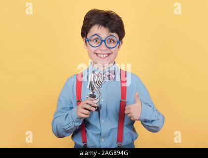 Happy boy with winning cup on yellow background Stock Photo