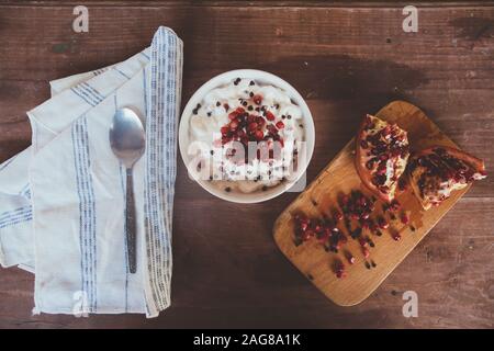 High angle shot of pomegranate fruit on a wooden board and a yogurt Stock Photo