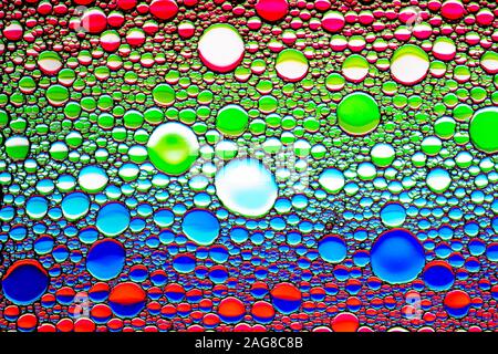 Top view on a colorful drops of oil on the water. Rainbow or spectrum colored circles, ovals. Abstract bright background for design with reflection an Stock Photo