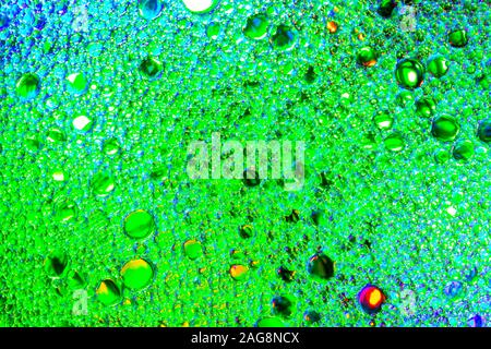 Colorful drops of oil on the water. Green colored circles, ovals. Abstract bright background for design. Stock Photo