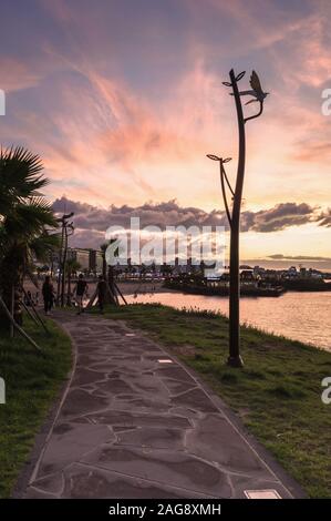 Jeju, South Korea, september 09, 2019: stone walkway to the Hamdeok Beach at susnet with people relaxing Stock Photo