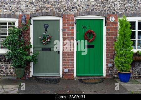 Christmas wreaths hanging from the wooden front doors on two English Brick cottages Stock Photo