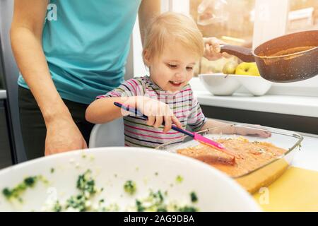 mother and daughter cooking vegetarian lasagne together in home kitchen Stock Photo