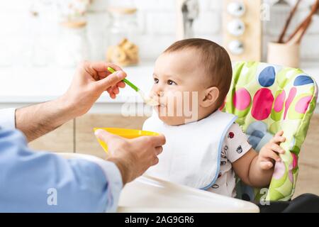 Toddler eating healthy kid food at kitchen interior Stock Photo