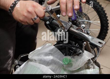 Master collects the motorcycle from the container. The process of removing the rigid attachment for installing the steering wheel of a motorcycle. Stock Photo