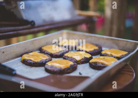 Selective focus shot of hamburger meats with cheese on a tray Stock Photo