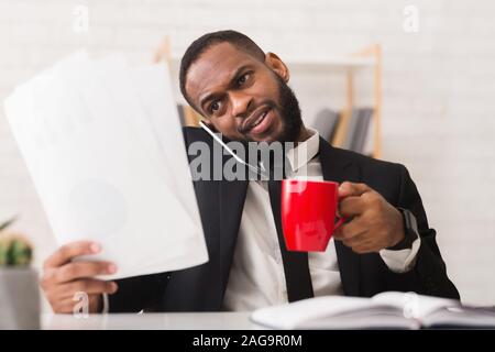 Angry manager checking on report, talking by phone in morning Stock Photo
