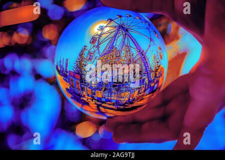 A selective focus shot of a crystal ball reflecting a ride from a theme park Stock Photo