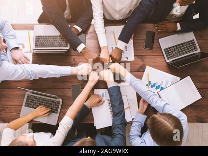 Fist bump of corporate team at meeting in office, top view Stock Photo