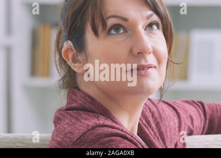 Smiling deaf woman wearing hearing aid Stock Photo