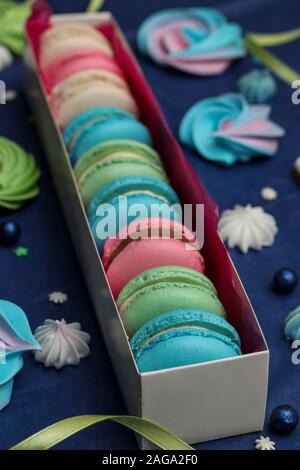 Tasty multi-colored sweet macaroons in a white gift box on a classic blue background, vertical orientation Stock Photo