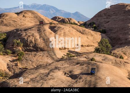 A 4x4 Hummer tour on the Hell's Revenge Trail in the Sandflats Recreation Area near Moab, Utah.  Approching is a 4WD side-by-side OHV. Stock Photo