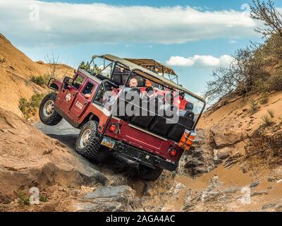 A Hummer lifts a tire climbing during a 4x4 Hummer tour on the Hell's Revenge Trail in the Sandflats Recreation Area near Moab, Utah. Stock Photo