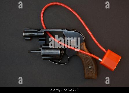 Black snubnose revolver with cable lock isolated on black background. Stock Photo