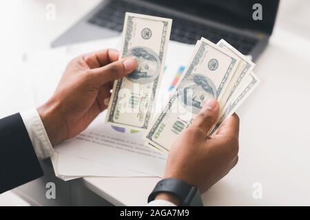 Cropped of businessman counting dollar banknotes at workplace Stock Photo
