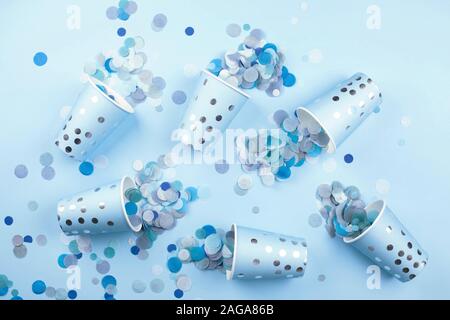 Beautiful festive cups with colorful confetti scattered on blue pastel background. Flat lay style. Holiday concept. Stock Photo