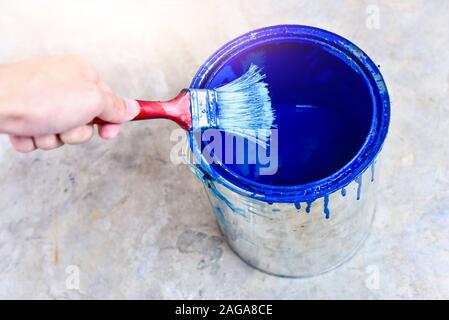 Hand Holding Paint Brush Over Paint Bucket for DIY Works Stock Photo