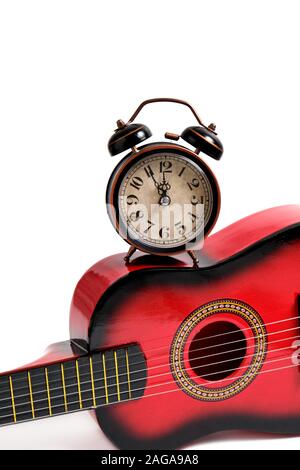 Children's six-string guitar and old retro alarm clock on white background. Stock Photo