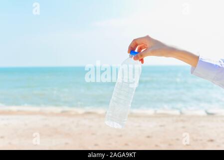 Hand Holding Plastic Bottle with Beach as Background for Environmental Pollution of Sea Concept Stock Photo