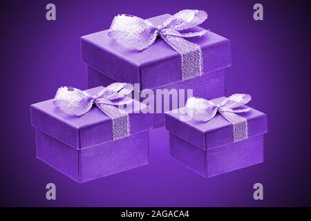 three purple gift boxes on a purple gradient background. close up. Stock Photo