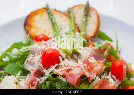 lettuce mixed with fried pancetta grated cheese, soft cheese and tomatoes. as decoration asparagus and bread Stock Photo