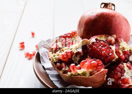 close-up, ripe pomegranates on a brown ceramic bowl on a white wooden table Stock Photo
