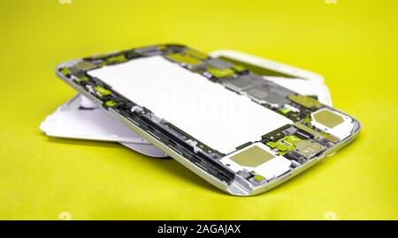 Close-up disassembled mobile phone parts. Tablet repair. Colorful yellow background. Stock Photo