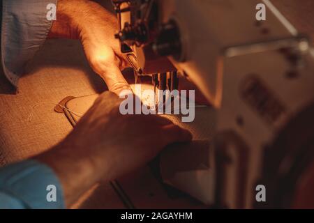 Professional leatherworker making a leather clothing with a sewing machine Stock Photo