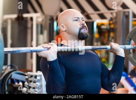 Brutal middle aged man lifting a barbell in gym. Strong and healthy lifestyle concept Stock Photo