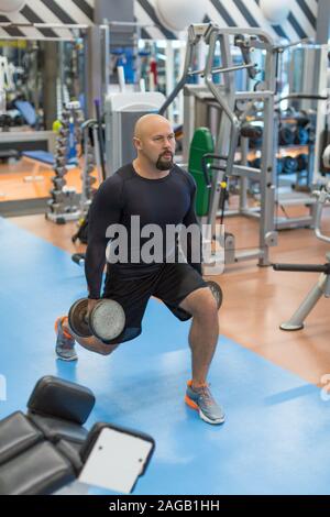 Middle aged man doing exercise for legs. Man working out legs with dumbbells. Healthy lifestyle and motivation concept. Stock Photo