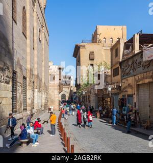 Cairo, Egypt- December 14 2019: Moez Street with local visitors Mosque of Sultan Barquq and Sabil-Kuttab of Katkhuda historic building at the far end, Gamalia district, Old Cairo Stock Photo