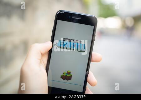 Bangkok, Thailand - December 16, 2019: Apple iPhone 7 held in one hand showing its screen with Minecraft Earth application. Stock Photo