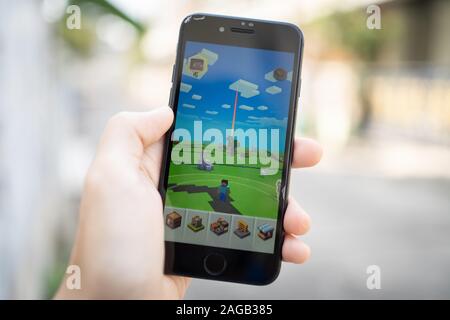 Bangkok, Thailand - December 16, 2019: Apple iPhone 7 held in one hand showing its screen with Minecraft Earth application. Stock Photo