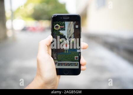 Bangkok, Thailand - December 16, 2019: Apple iPhone 7 held in one hand showing its screen with Minecraft Earth application. Stock Photo